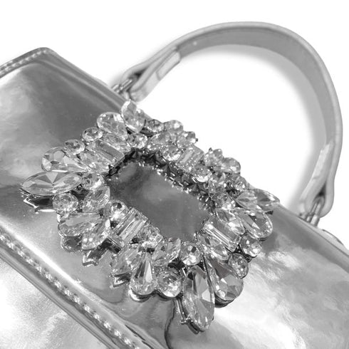 Close-up of a silver clutch with a decorative gemstone embellishment on a white background