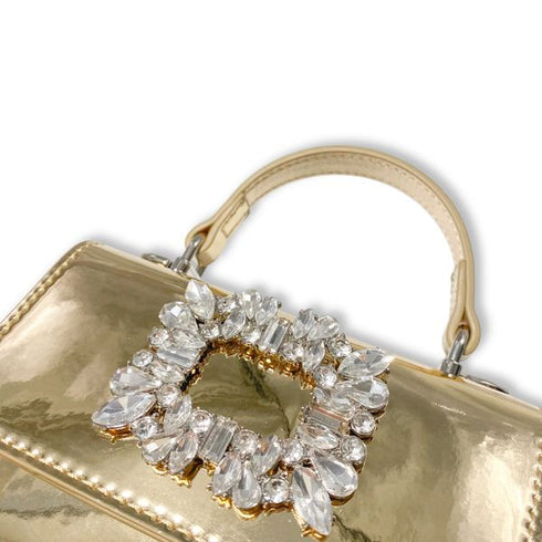 Gold handbag with a decorative crystal heart clasp on a white background