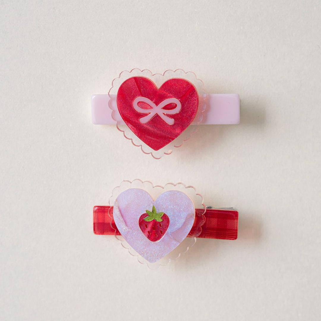 set of heart clips: one with a pink bow in the center and the other with a red strawberry 