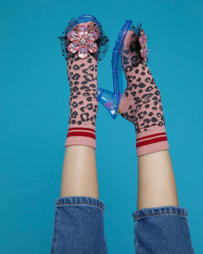 little girl posing with the play shoes on with her feet in the air. she is modeling them wearing leopard socks underneath her shoes. 