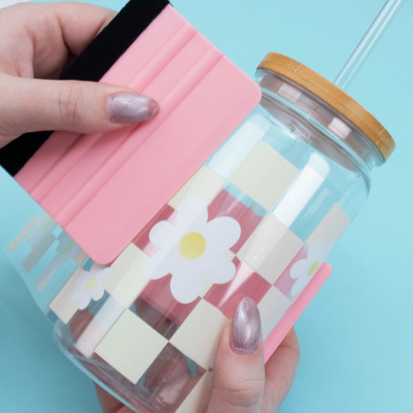 Glass jar with wooden lid and daisy design on a blue background