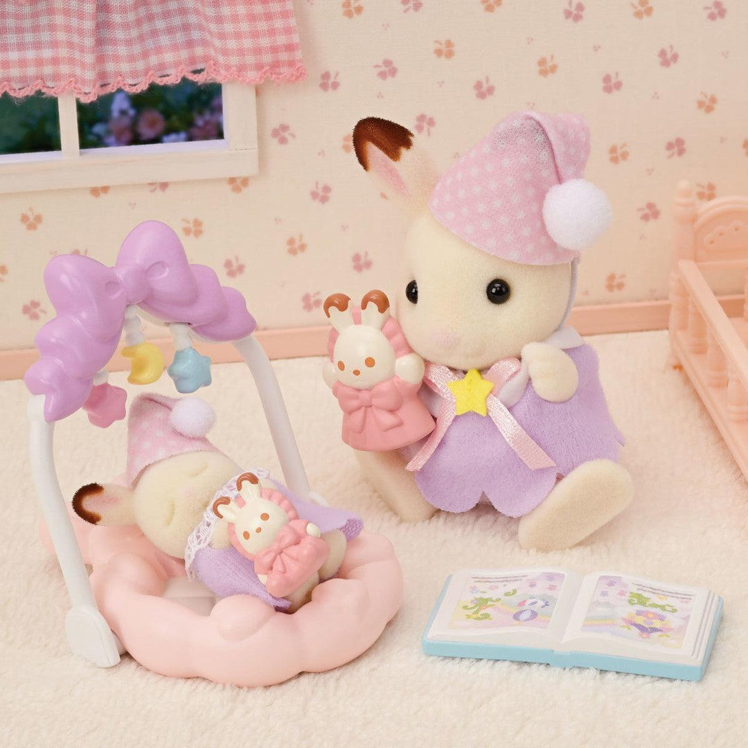 this picture shows a scene of the big sister bunny putting baby bunny to sleep in a nursery