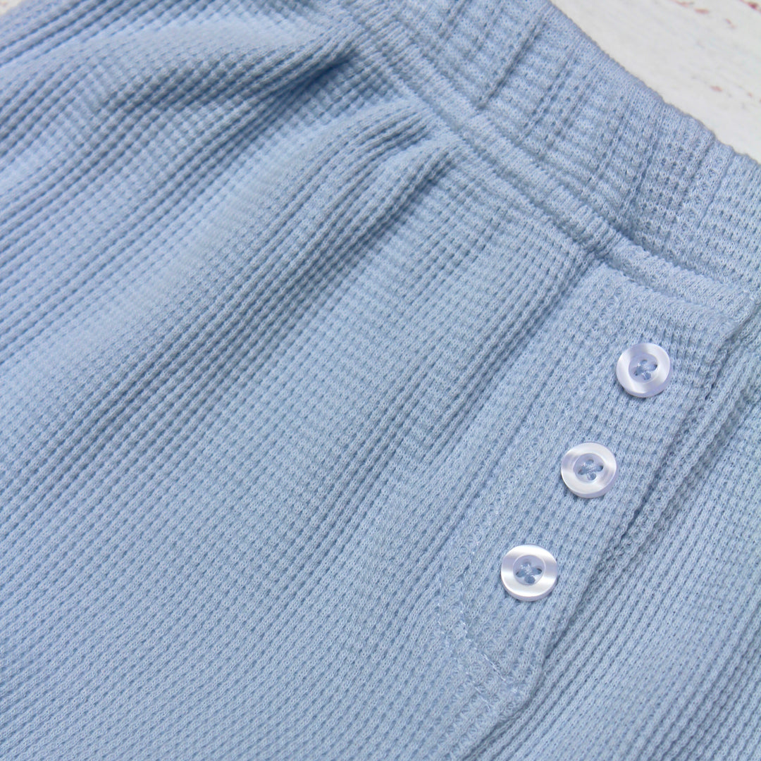 Close-up of blue textured fabric with buttons on a white background