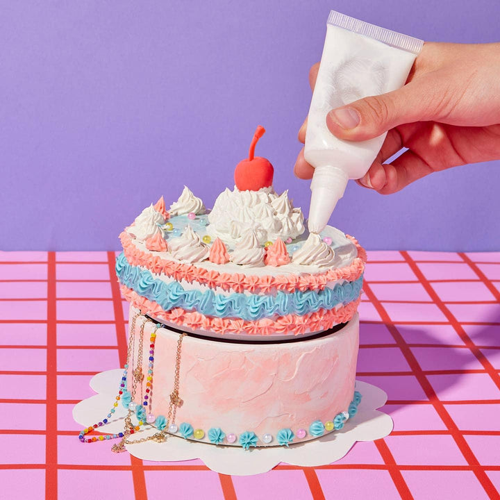 this picture shows someone using a special container to add the frosting to the cake. 