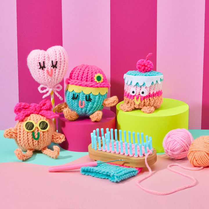 Colorful crochet toys with a loom and yarn on a pink and green striped background