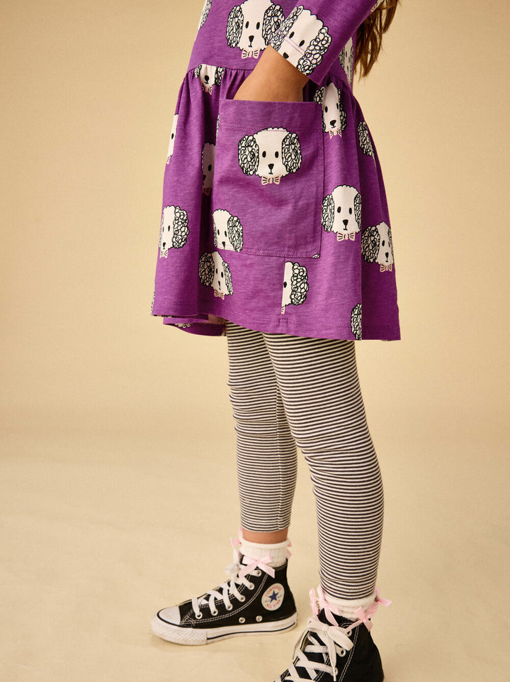 Purple dress with hedgehog pattern and striped leggings on a beige background