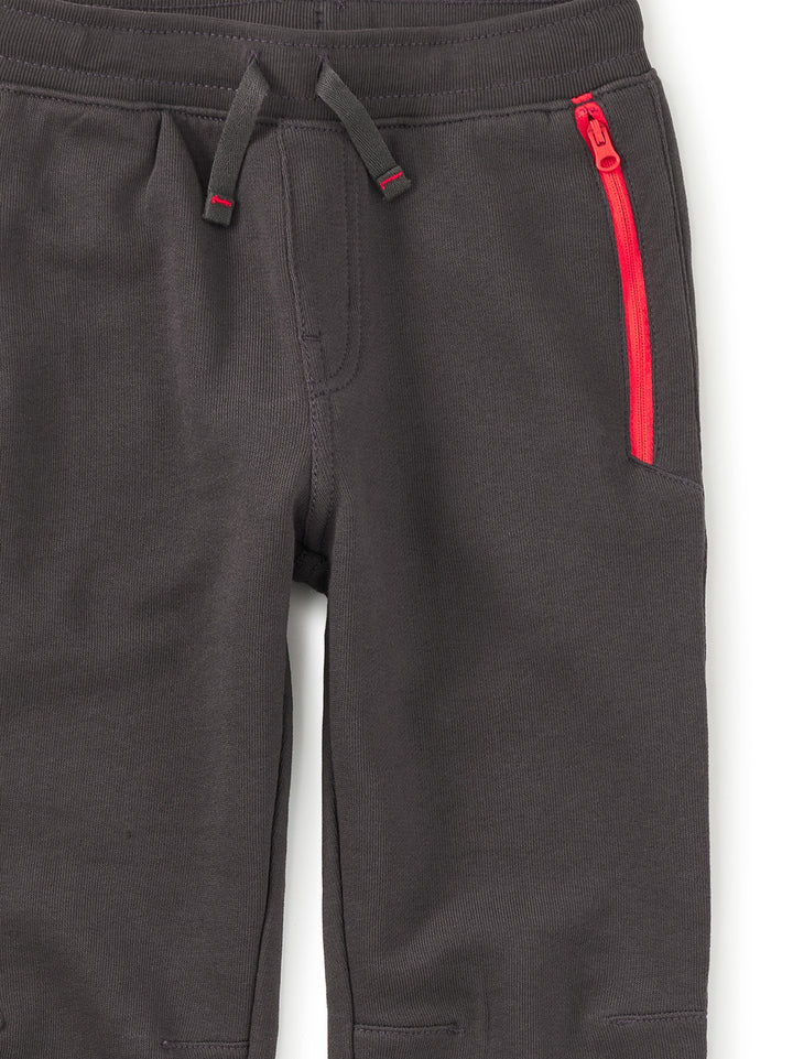 Dark gray pants with a red zipper on a white background