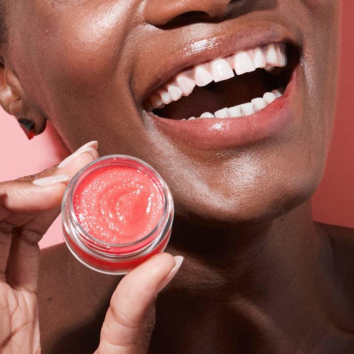 lip balm pot with pink lip balm and glossy lips. 