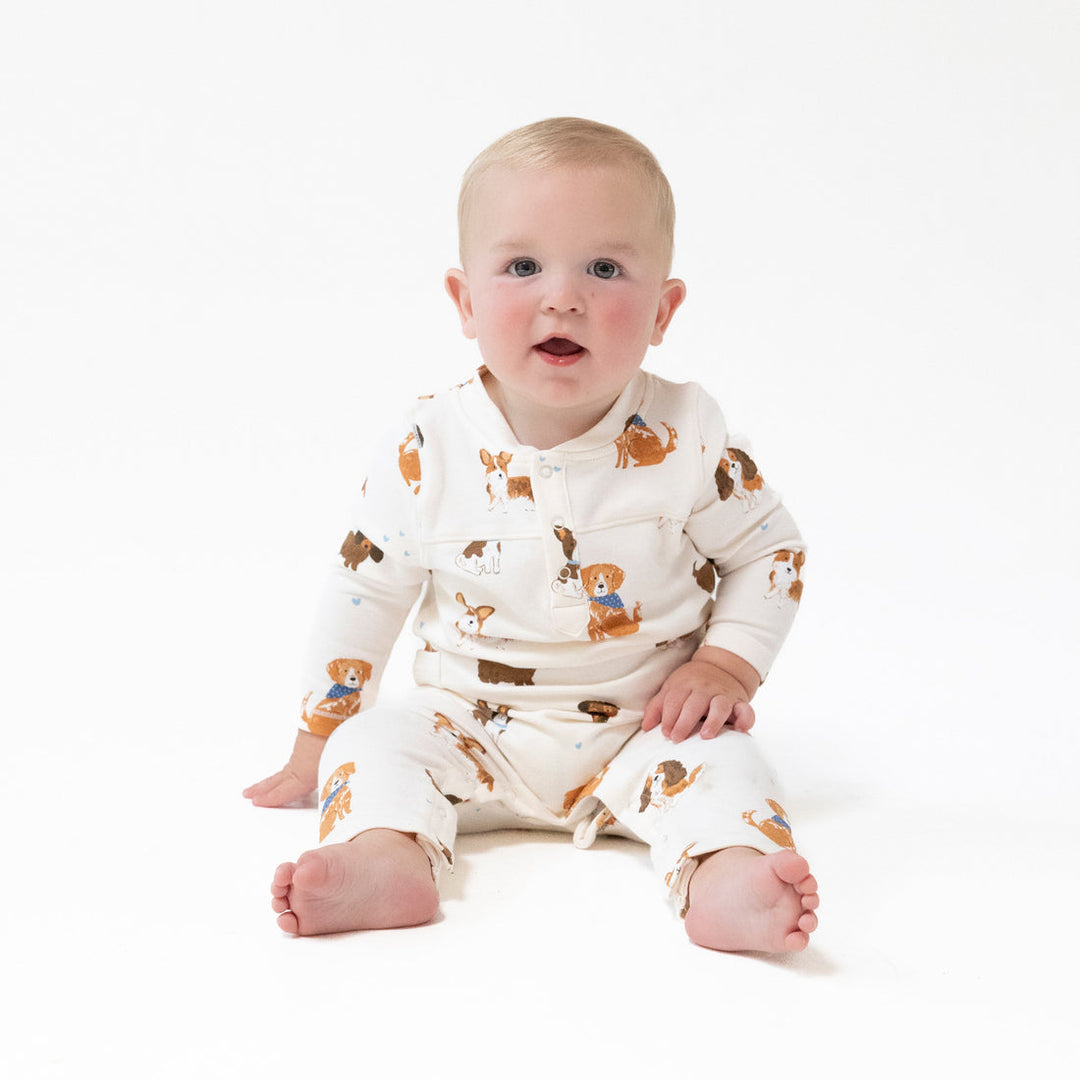 Baby wearing a white outfit with brown bear patterns on a white background