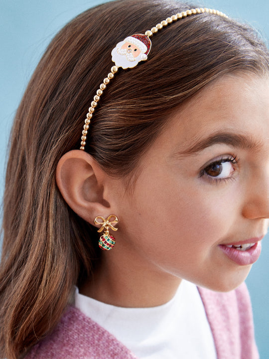 Close-up of a person wearing a decorative headband and earrings against a light blue background