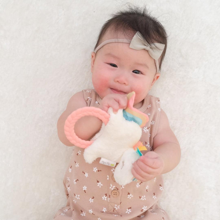baby playing with the unicorn plush teether 