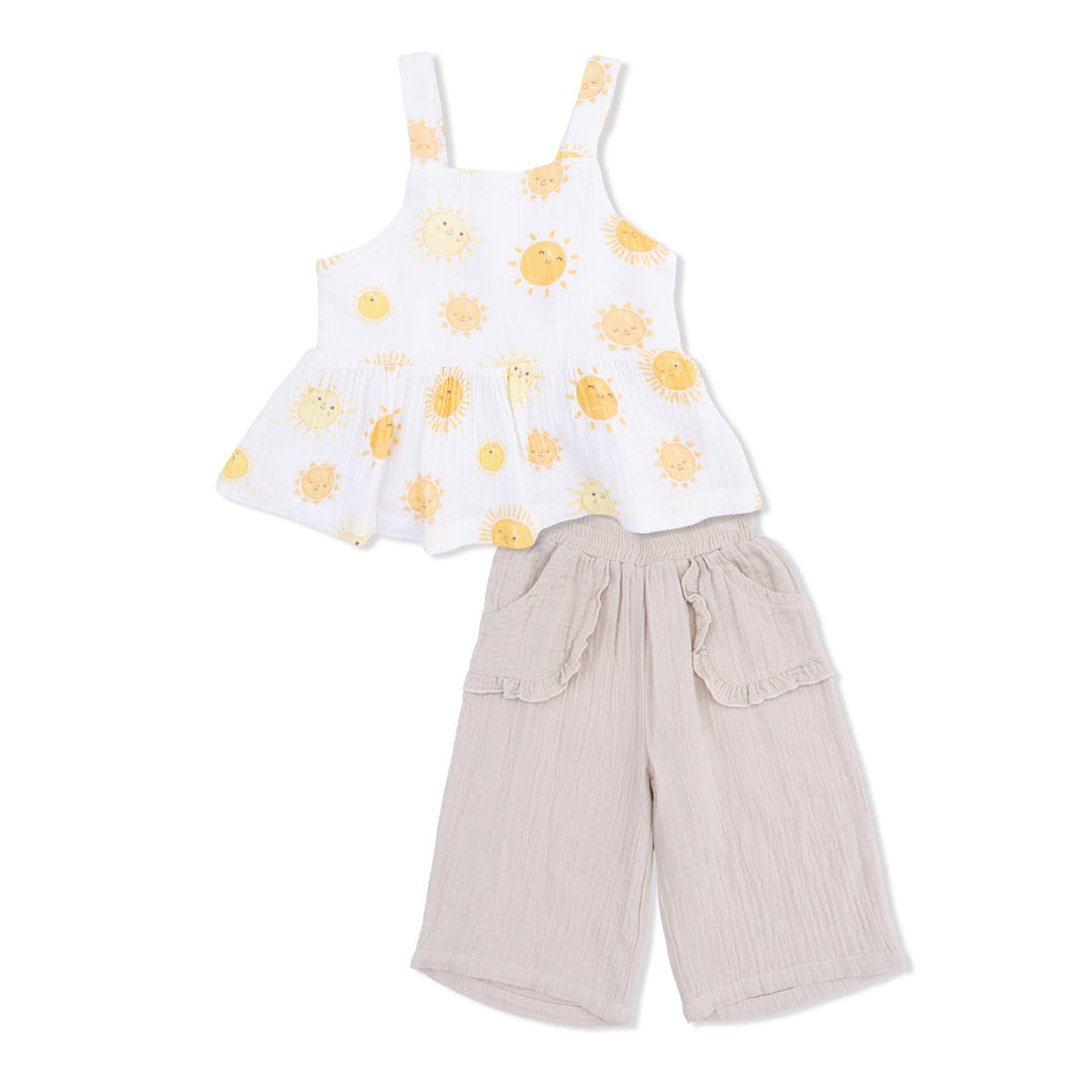 Children's outfit with yellow suns on the  top and beige pants on a white background