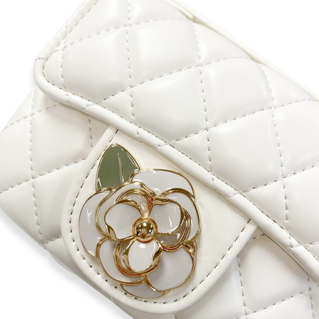 White quilted handbag with a floral emblem on a white background