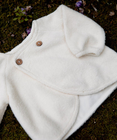 close up of the material of the beige jacket/sweater with button closure. 