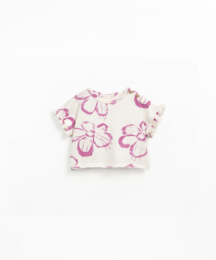 ivory cotton tee with ruffle edges on sleevces. big pink flowers on the top. 