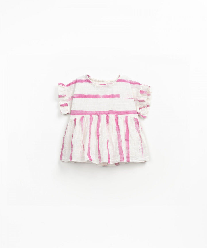 ivory top with ruffles at the sleeve edge with empire waisted top and flowy bottom. dark pink stripes painted across the chest and vertical stripes painted down the bottom. 