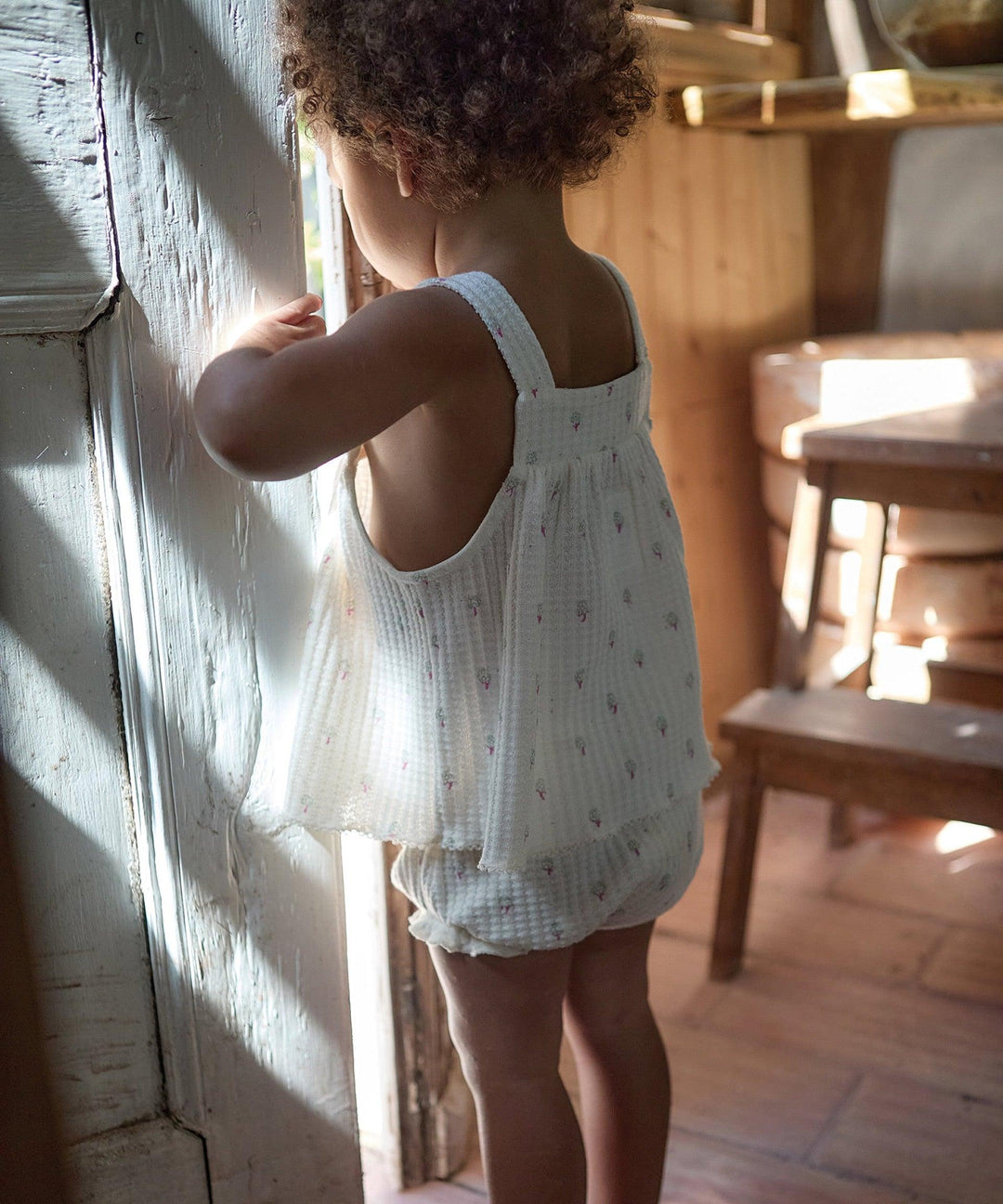 picture of baby girl wearing the ribbed outfit in white colorway instead of blue. the top is tunic length and looks lightweight 