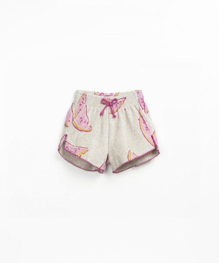 pair of plush shorts, beige color with pink watermelons all over it. edges of shorts finished in fuschia threads. 
