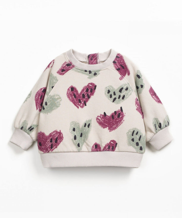 Children's sweater with pink and green heart patterns on a white background