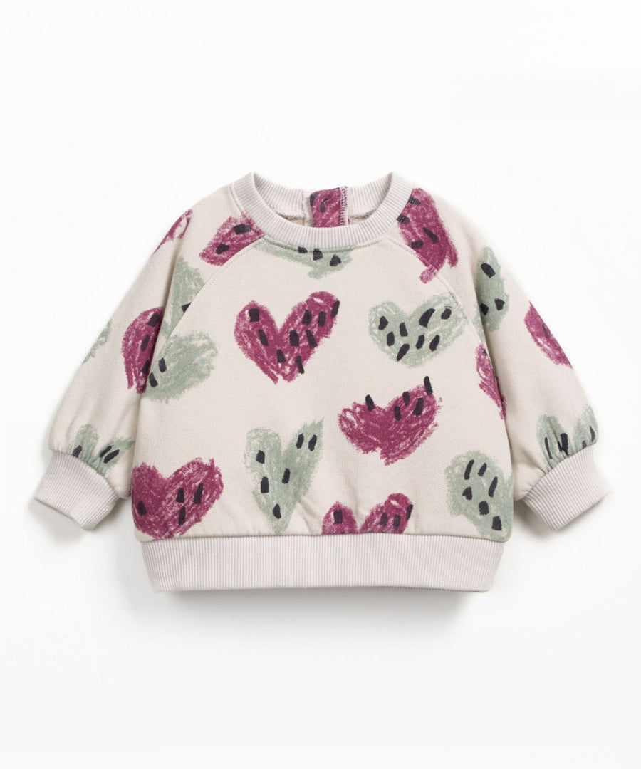 Children's sweater with pink and green heart patterns on a white background