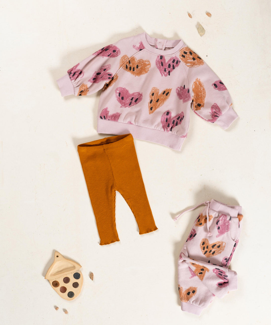 Children's outfit with pink sweater and orange pants on a white background