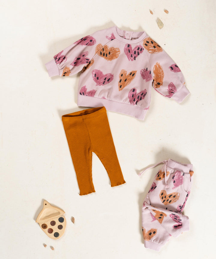 Children's outfit with pink sweater and orange pants on a white background