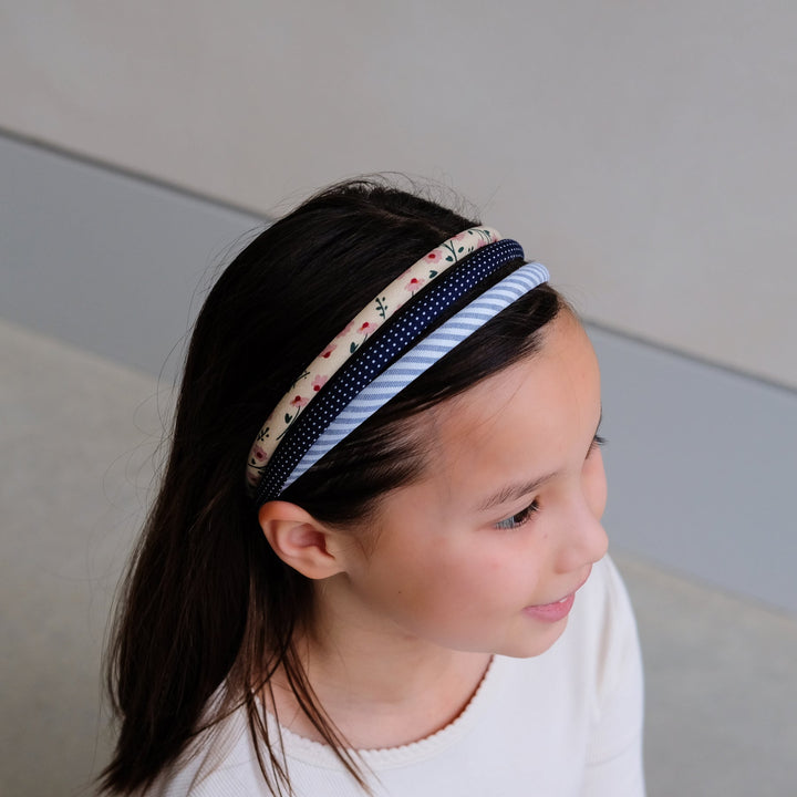 Person wearing a patterned headbands against a neutral background