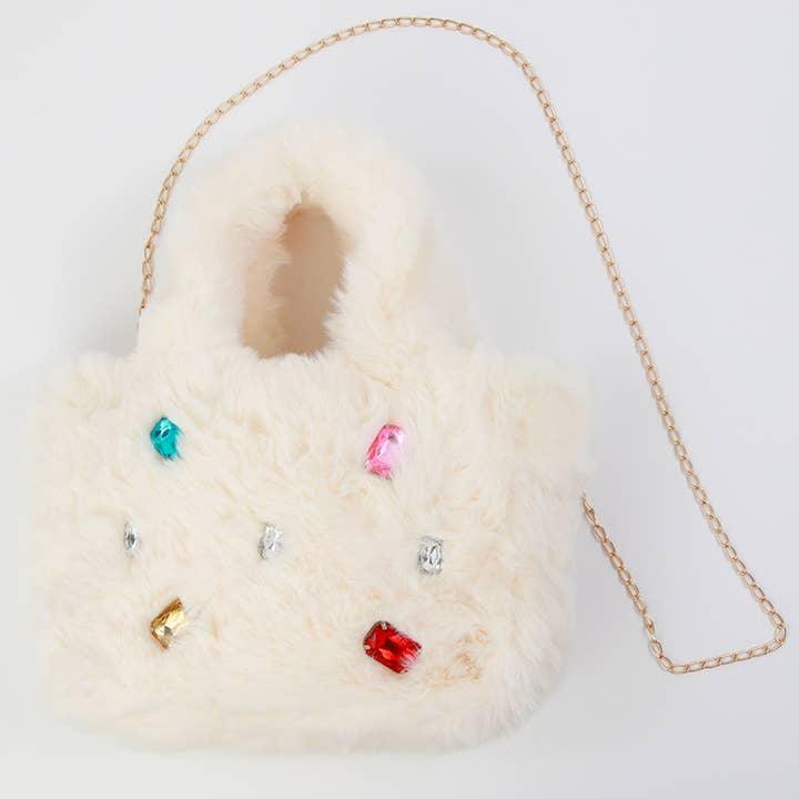 furry biege bag with handle and detachable gold strap. rhinestone jewels adorn the front of the bag