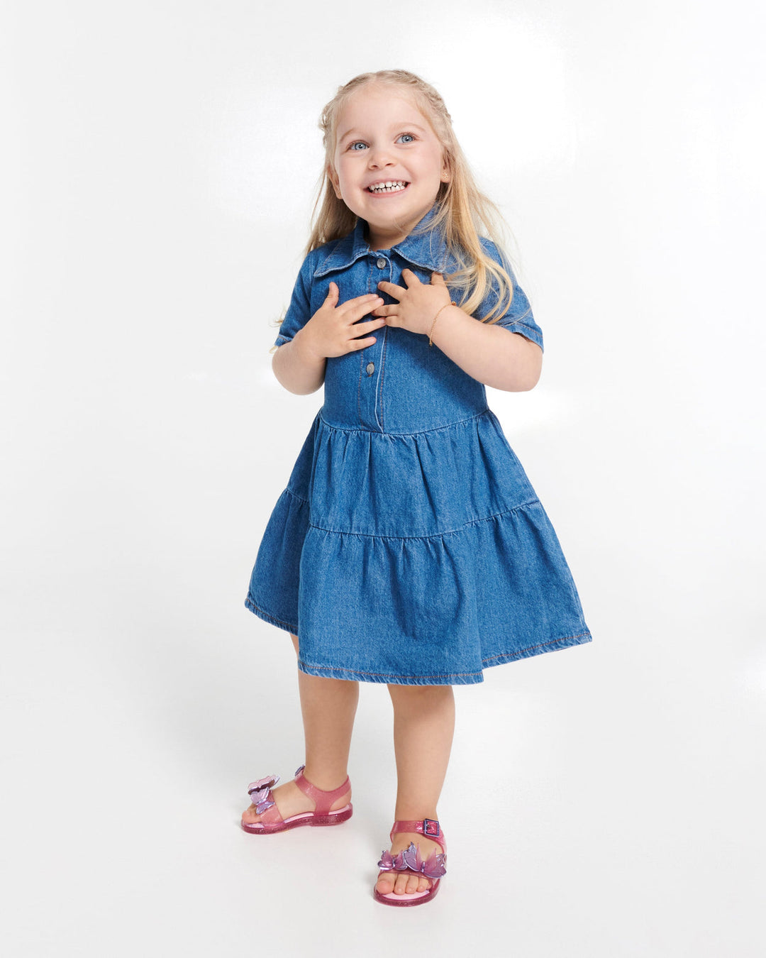 Young girl wearing a blue denim dress on a white background
