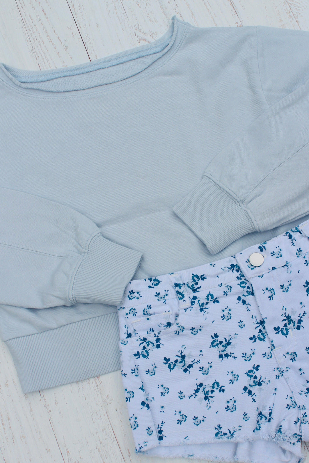 baby blue sweatshirt with white cutoffs and navy floral design on the shorts. 