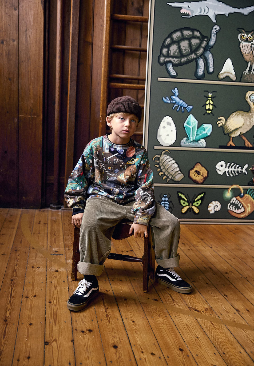 Child sitting on a chair in front of a chalkboard with educational drawings.