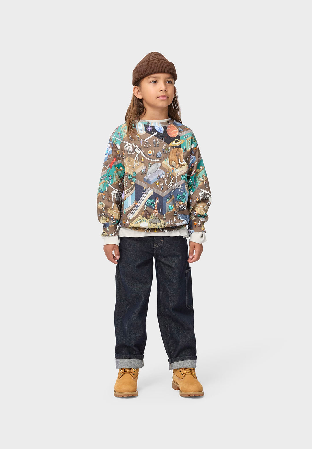 Child wearing a patterned sweatshirt dark pants, and brown boots on a white background