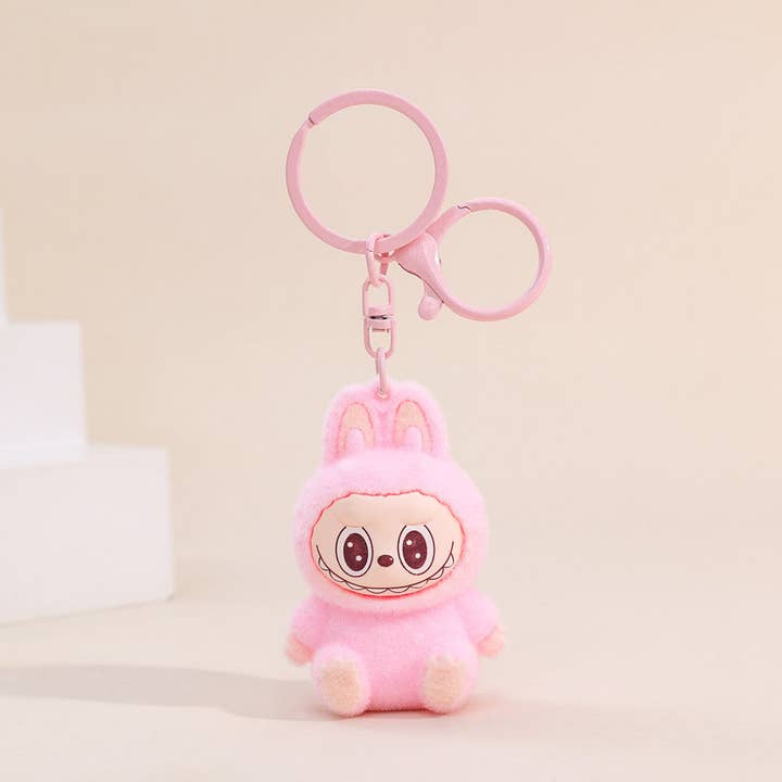 labubu figure keychain with a cartoon character in a pink outfit on a light beige background
