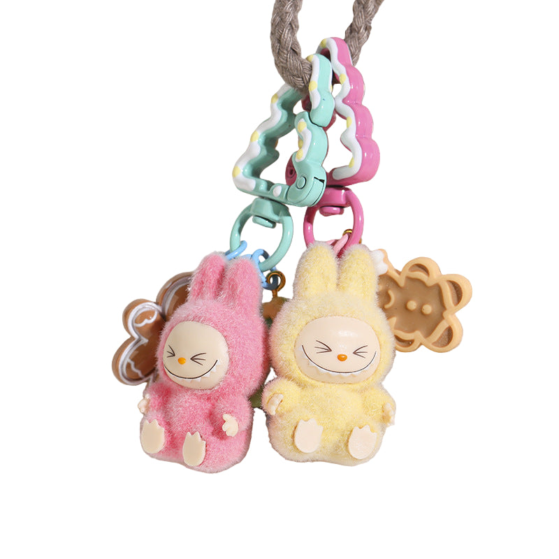 Two plush keychains, one pink and one yellow, on a textured white surface.
