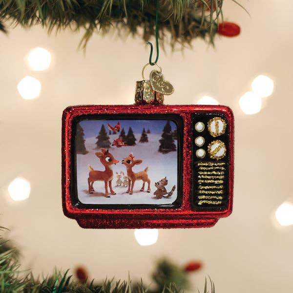 Decorative ornament shaped like a vintage television set with Christmas scene on screen, hanging on a Christmas tree.