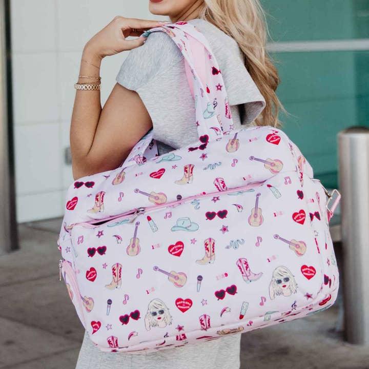Taylor Swift inspired duffel bag with shoulder straps and external pocket. Taylor Swift inpsired icons all over the bag: guitar, heart shaped sunglasses, red lipstick, microphone