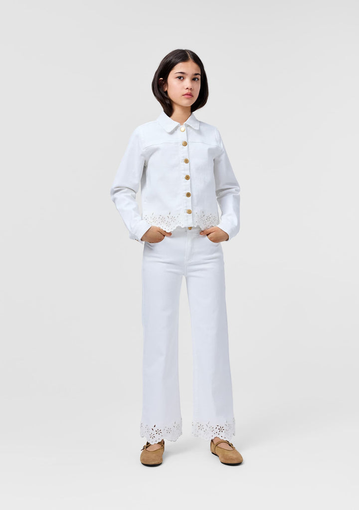 Woman wearing a white embroidered jacket and pants on a white background
