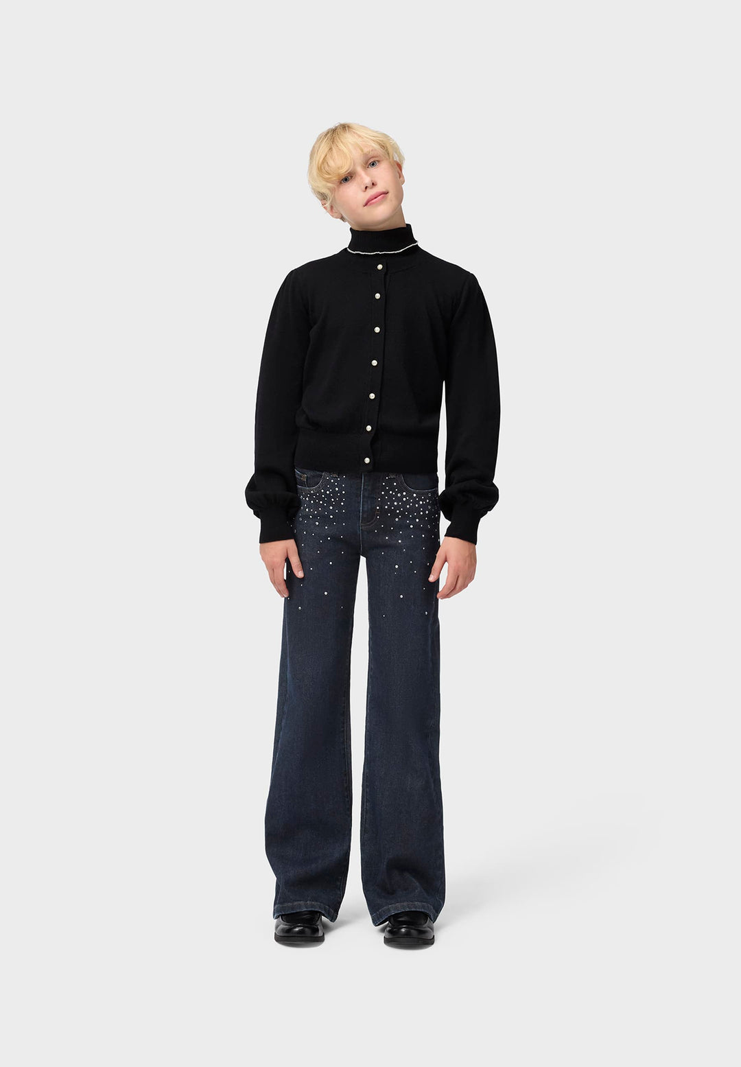 Person wearing a black sweater and dark jeans on a white background