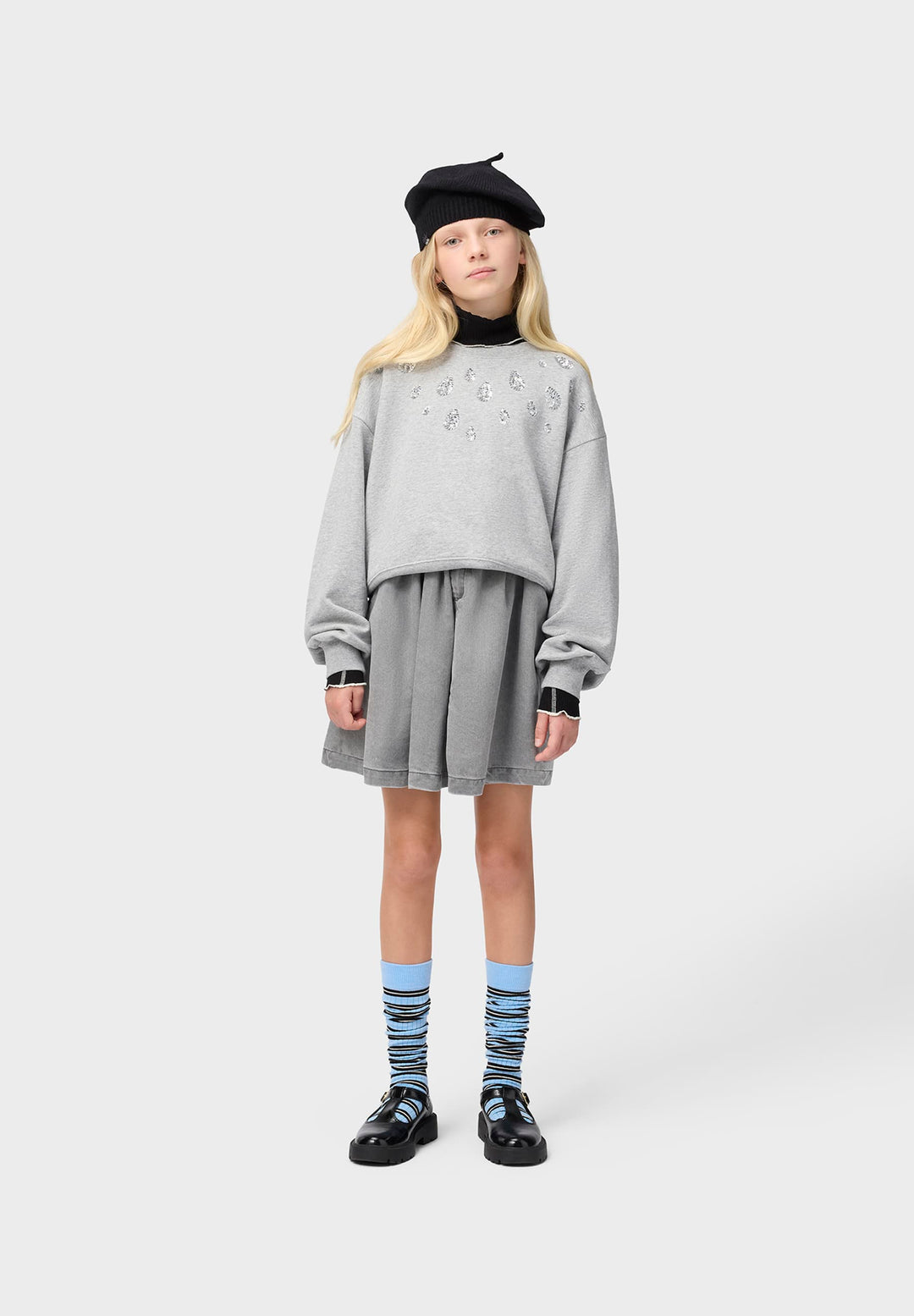 Person wearing a gray outfit with a black beret on a white background