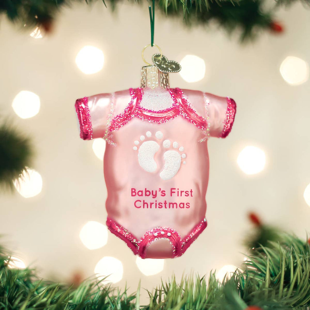 Pink baby onesie ornament with 'Baby's First Christmas' text on a Christmas tree.