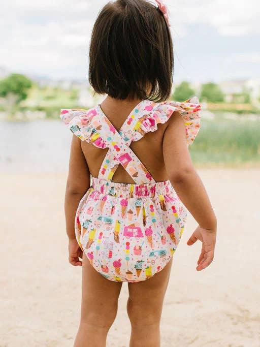 back of the romper, with criss cross straps and ruffles on the sleeves. the print has ice creams on it and ice cream trucks. 