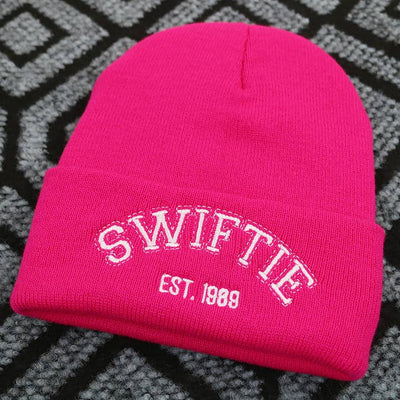 dark pink beanie with 'Swiftie' written in white embroidery on the hat