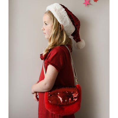 Little Girl modeling the santa hat and bag from the side. 