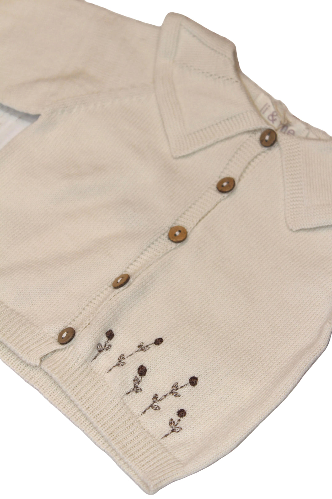 Beige knitted cardigan with brown buttons on a wooden surface