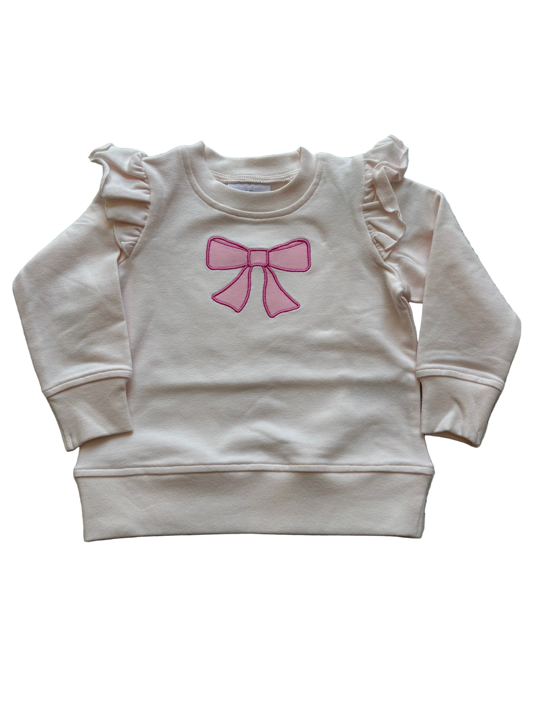 Beige sweatshirt with a pink bow design on a wooden surface