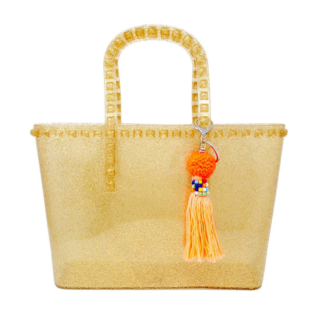 giant jelly tote bag in gold glitter with handles and detachable tassel strap at the handle. 