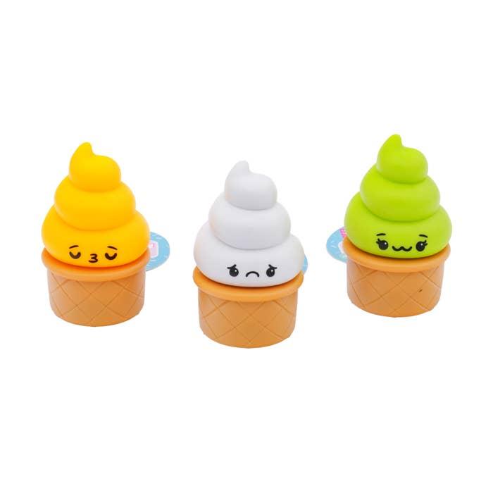 pull back ice cream cones in differnt colors: bright orange, white and green. each has a different facial expression on it. 
