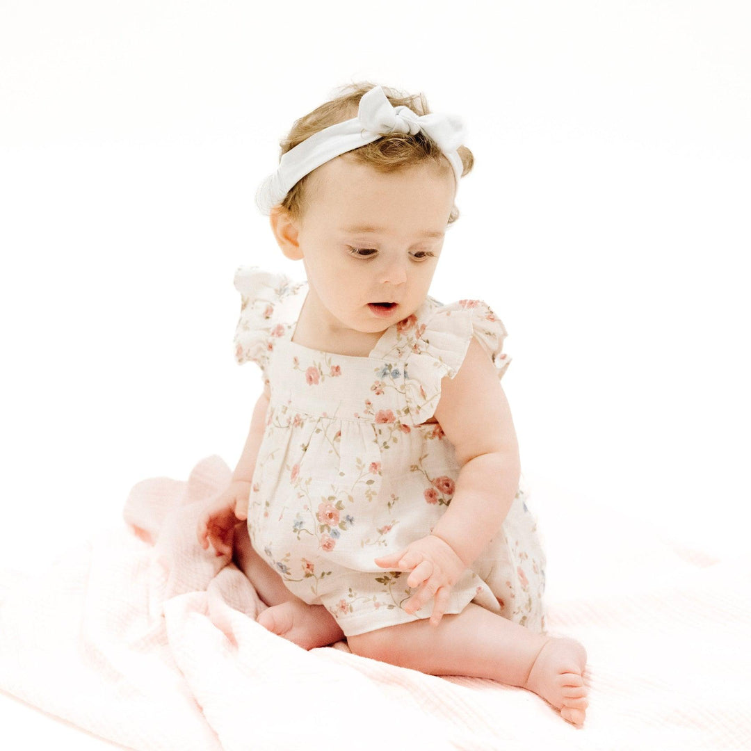 little baby sitting in the climbing roses pinafore. 