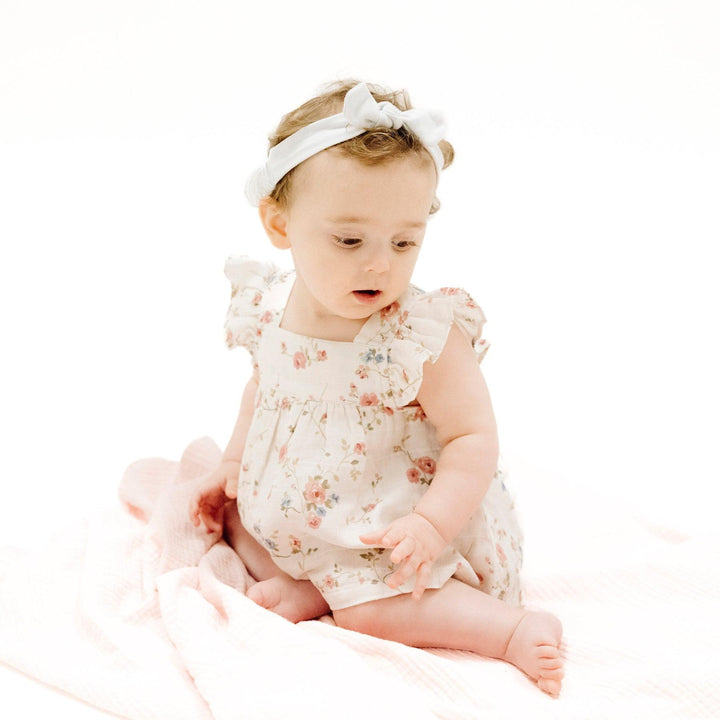 little baby sitting in the climbing roses pinafore. 