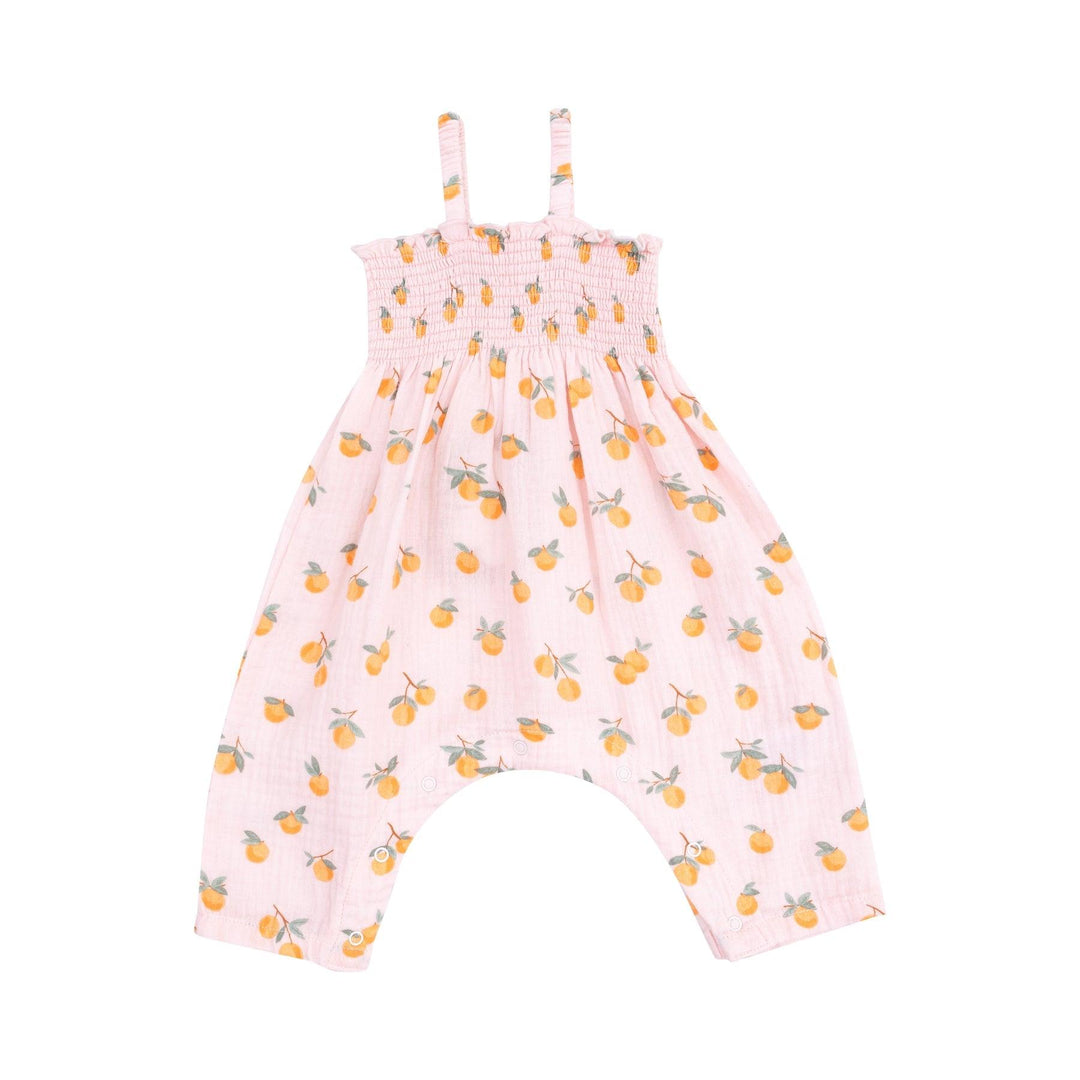 pink smocked romper with tiny oranges printed all over it with spaghetti straps and easy access for diaper changes